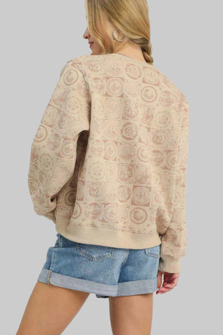 Woman wearing a beige patterned sweater and denim shorts on a white background