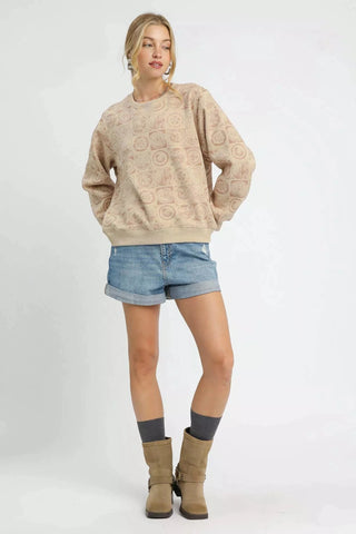 Woman wearing a beige textured sweater, denim shorts, and brown boots on a white background