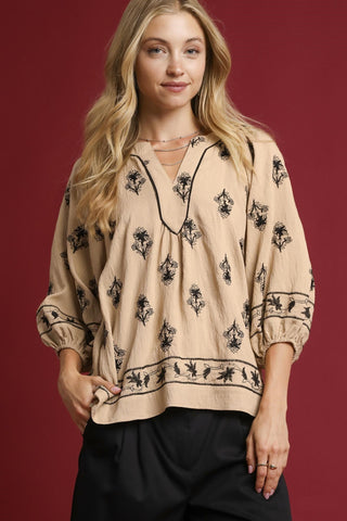 Woman wearing a beige blouse with black floral patterns on a red background