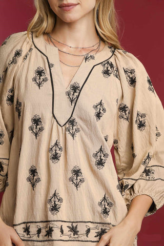 Beige blouse with black floral patterns on a red background
