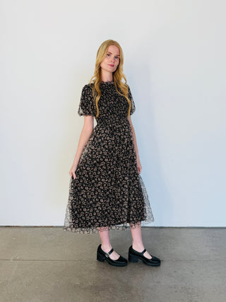 Woman wearing a black floral dress against a white background