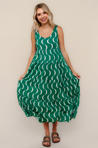 Woman wearing a green dress with white wave pattern against a beige background