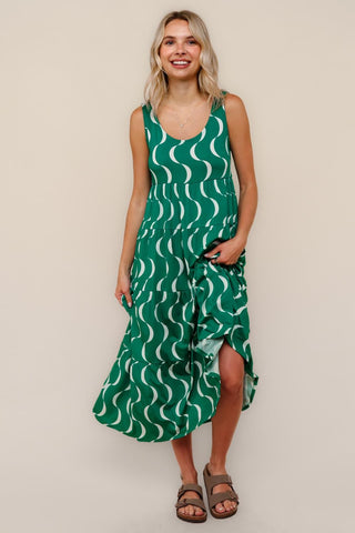 Woman wearing a green dress with white wave pattern against a beige background