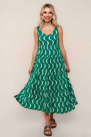 Woman wearing a green dress with white wave pattern against a beige background