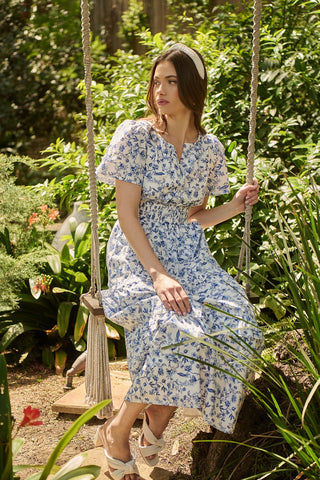 Woman in a floral dress sitting on a swing in a garden