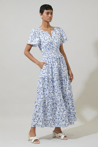 Woman wearing a blue floral dress against a plain background